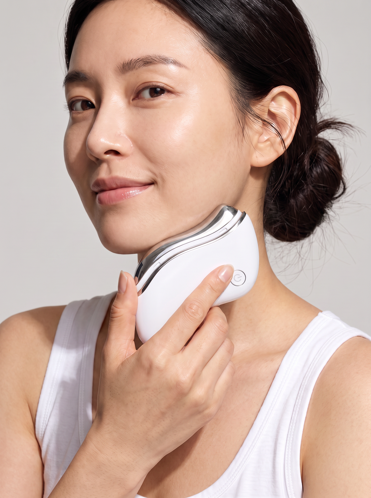 Woman gliding the Advanced Electronic Gua Sha along her jawline