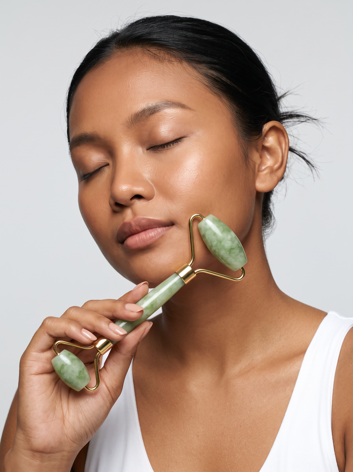 Woman using the Radiance Sculpt jade roller along her jaw